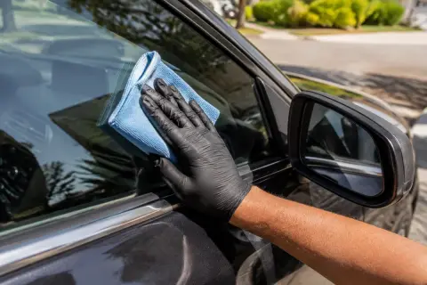 Microfiber cloth cleaning a car window and side mirror