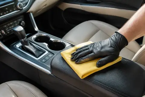 Microfiber cloth wiping a car center console and armrest
